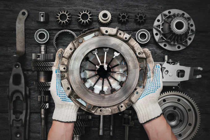 Skilled technician holding clutch pressure plate with precision transmission parts